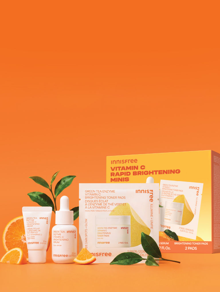Innisfree Vitamin C Brightening Minis set arranged on a bright orange background with orange slices and green tea leaves