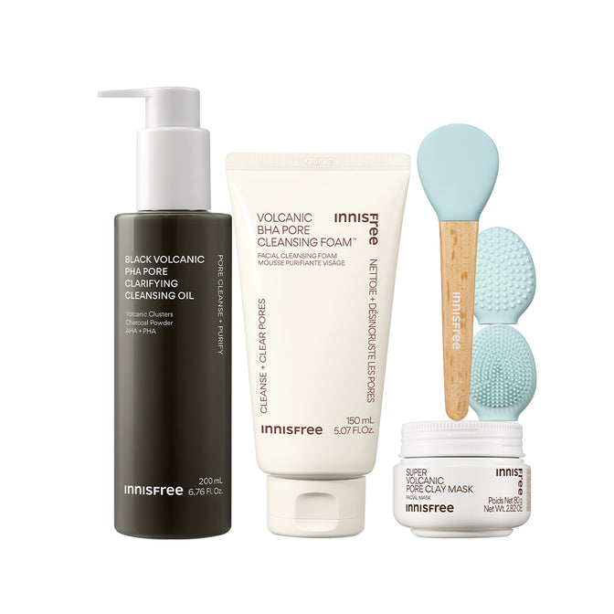 The Volcanic Pore Care Routine featuring Black Volcanic PHA Pore Cleansing Oil, Volcanic BHA Pore Cleansing Foam, two light blue silicone cleansing brushes with wooden handles, and a Super Volcanic Pore Clay Mask jar, all on a white background.