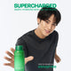 Enlarge image of Korean Idol MINGYU in a black shirt extends his hand toward Green Tea Ceramide Milk, with large green text reading &amp;#39;SUPERCHARGED&amp;#39; and smaller text &amp;#39;DEEPLY HYDRATED SKIN - NO OFF HOURS&amp;#39; on a clean white background.
