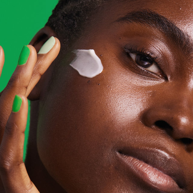 A person applying cream to their cheek.