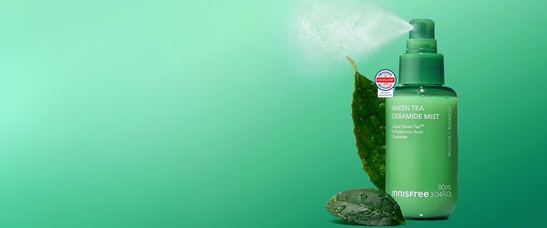 Green Tea Ceramide Mist with a leaf and stone prop, shown on a bright green gradient background with mist coming from the sprayer.