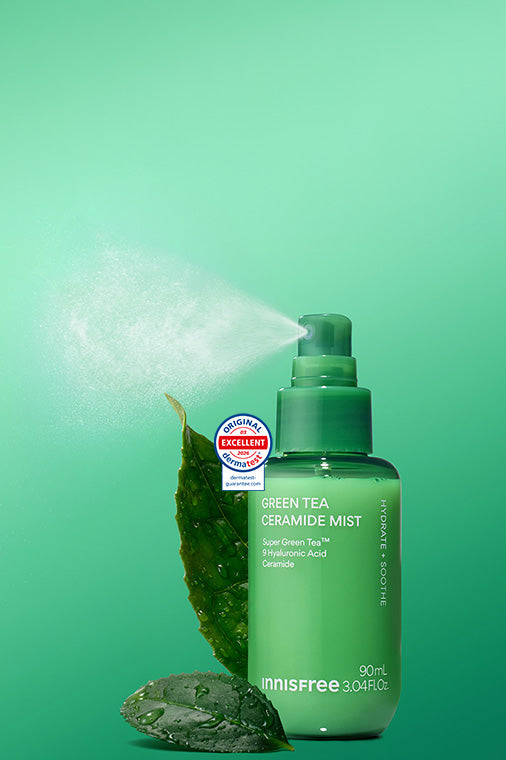 Green Tea Ceramide Mist with a leaf and stone prop, shown on a bright green gradient background with mist coming from the sprayer.
