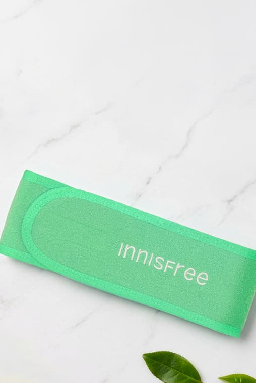 innisfree green spa headband on a texture background with green leaves