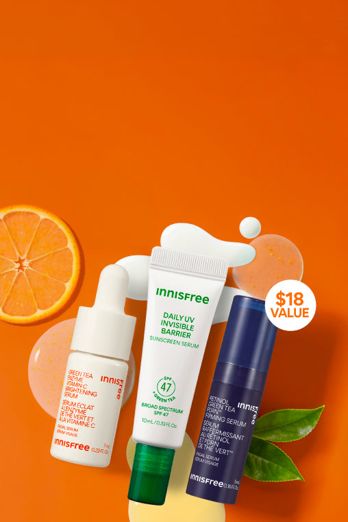Three Innisfree skincare products arranged on a bright orange background with decorative citrus and leaf props: Vitamin C Serum 7mL, Green Tea Sunscreen Serum 10mL, and Green Tea PDRN™ Serum 5mL. A circular badge says '$18 VALUE'.
