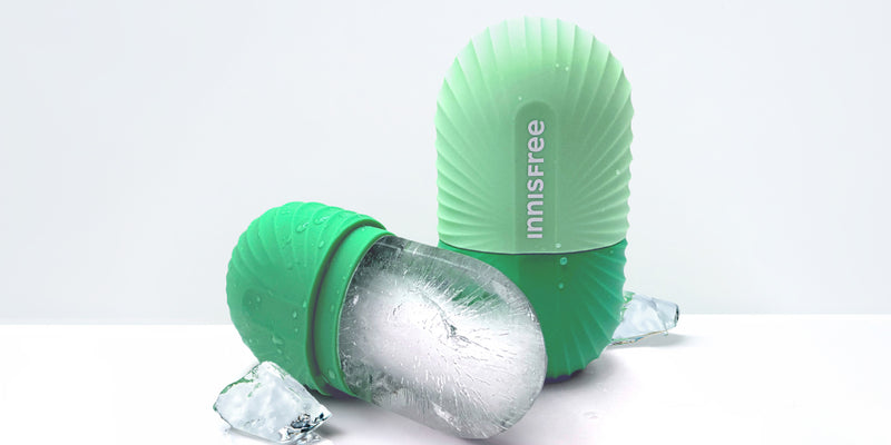 A mint green Innisfree silicone ice mold shown with one mold upright containing a frozen ice cube and another lying on its side, photographed on a clean white background.
